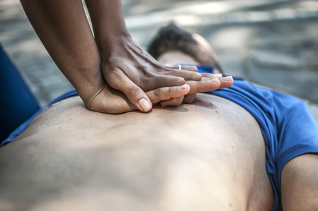 Girl making cardiopulmonary resuscitation to an unconscious guy after heart attackの写真素材