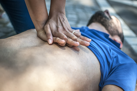 Girl making cardiopulmonary resuscitation to an unconscious guy after heart attackの写真素材