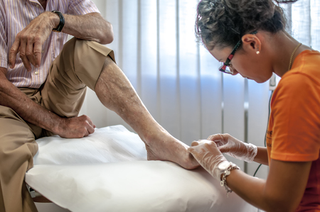 podiatry doctor curing an elderly patient foot