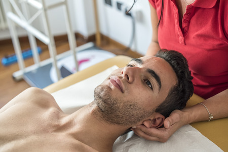 physiotherapist massages young patient to cure a cervical painの写真素材