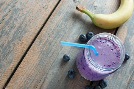 Blueberry smoothie in a jar with fruit on one sideの写真素材