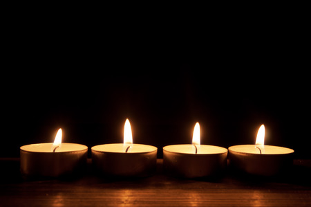 Row of lit candles in the darkの写真素材
