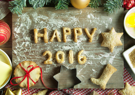 Happy 2016 made from cookies on top of a chopping board with baking ingredientsの写真素材
