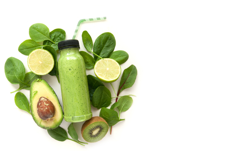 Bottled detox drink surrounded by green foods including spinach and kiwiの写真素材