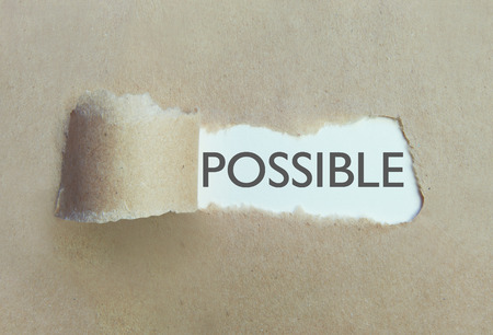 Torn brown paper uncovering the word possibleの写真素材