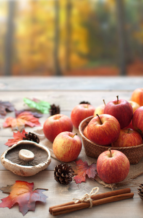Leaves, apples over a wooden table in an autumn forestの写真素材