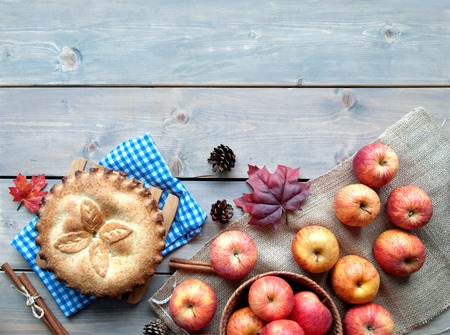 Apple pie with fruit ingredients and cinammon sticks on a wooden tableの写真素材