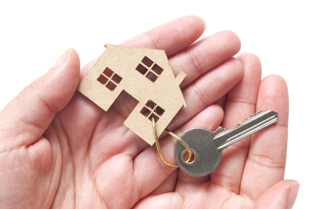Hands holding a miniature house attached to key ring, property real estate conceptの写真素材