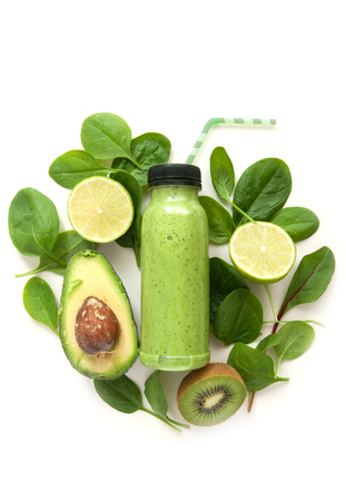 Bottled detox drink surrounded by green foods including spinach and kiwiの写真素材