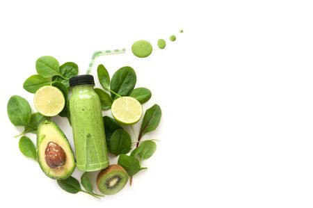 Bottled detox drink surrounded by green foods including spinach and kiwiの写真素材
