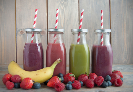 Flavoured smoothies in bottles in a rack over a wooden backgroundの写真素材