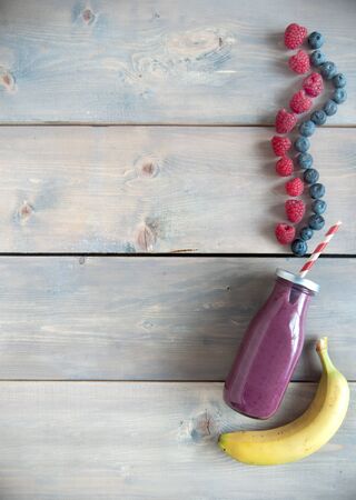 Berry flavoured smoothie in a bottle over a wooden background with copyspaceの写真素材