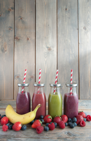 Flavoured smoothies in bottles in a rack over a wooden background with copyspaceの写真素材