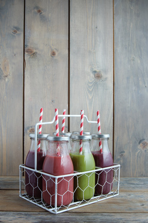 Flavoured smoothies in bottles in a rack over a wooden backgroundの写真素材