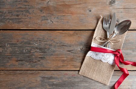 Rustic cutlery set with silk ribbon over a wooden backgroundの写真素材