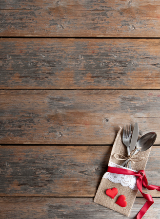 Fork and knife inside pouch with decorative red ribbon on top of a wooden tableの写真素材