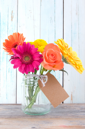 Bunch of flowers with blank gift label on wooden backgroundの写真素材