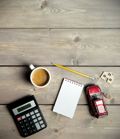 Blank notepad on a wooden table with a miniature car and houseの写真素材