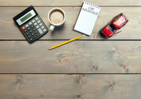 Notepad with car insurance handwritten on a table with a miniature carの写真素材