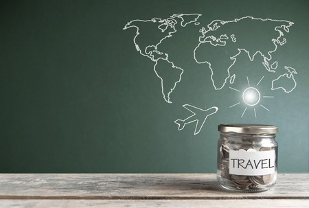 Travel savings jar by a chalkboard with a world mapの写真素材