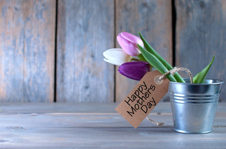 Mothers day tulips in a pot wooden background with space with gift labelの写真素材