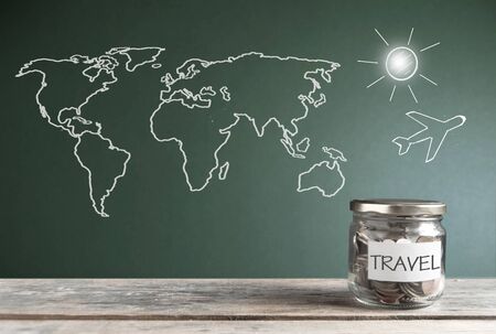 Travel savings jar by a chalkboard with a world mapの写真素材