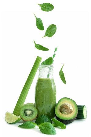 Leafy green greens falling into a smoothie bottle over a white backgroundの写真素材