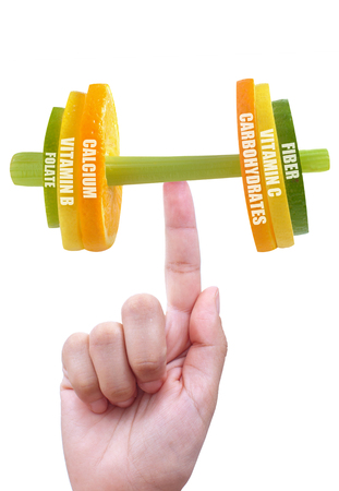 Fruit and vegetable dumbbell balanced on a finger with nutritional factsの写真素材