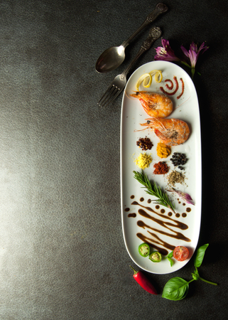Herbs and spices on a plate with cooked prawnsの写真素材
