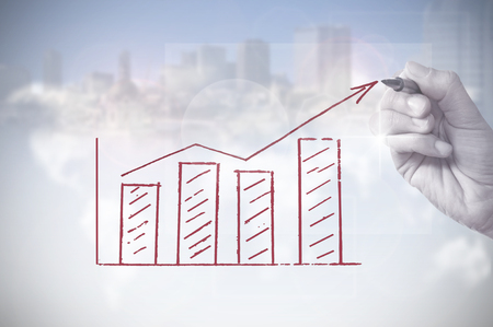 Hand drawing an upwards arrow business chart with skyscrapers in the backgroundの写真素材