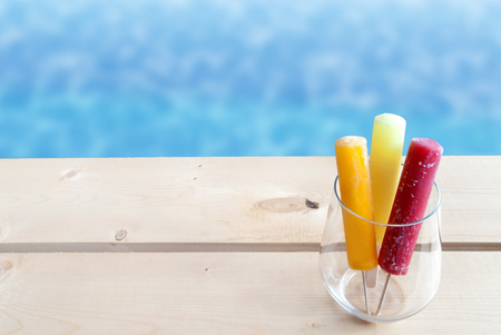 Frozen ice lollies in a glass by a swimming poolの写真素材