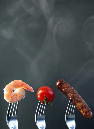 Barbecued ingredients including shrimp and sausage on forks with background spaceの写真素材