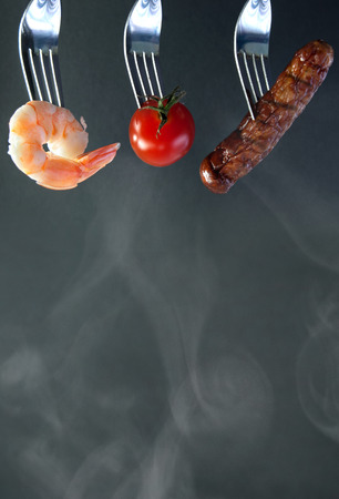 Barbecued ingredients including shrimp and sausage on forks with background spaceの写真素材