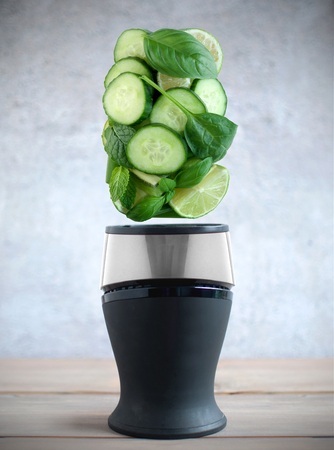 Fresh green fruits and vegetable ingredients hovering above a blenderの写真素材