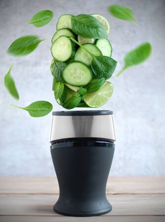 Fresh green fruits and vegetable smoothie ingredients spinning around a blenderの写真素材