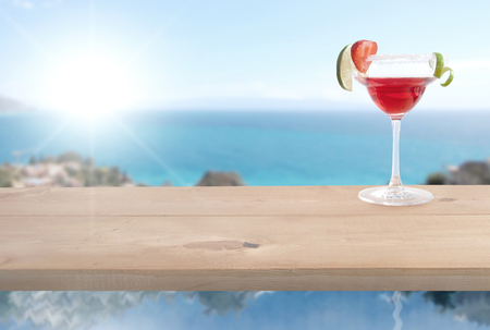 Red cocktail beverage with lime and ice by the coastの写真素材