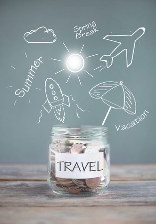 Jar of travel savings with sketches against a chalkboardの写真素材