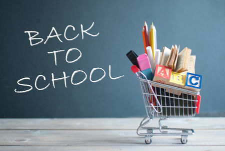 Shopping cart filled with stationery next to a chalkboardの写真素材