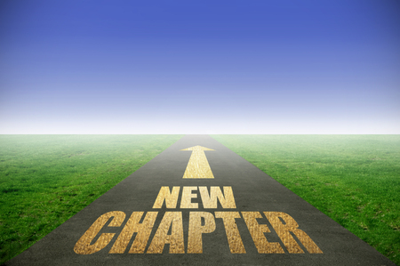 New chapter printed in gold on road with green grass on each sideの写真素材