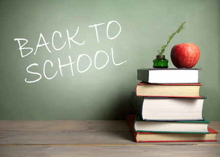 Back to school handwritten on chalkboard stack of books, apple and quillの写真素材