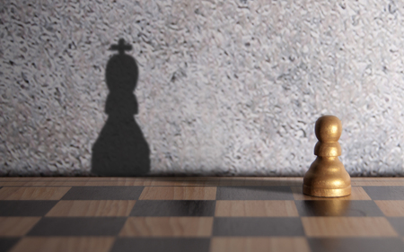 Chess king shadow emerging from a pawnの写真素材