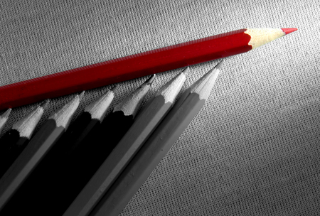 Red pencil standing out in a group of black and white pencilsの写真素材