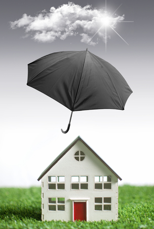 Umbrella protecting a house from bad weatherの写真素材