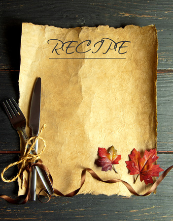 Recipe on paper scroll with fork and knife tied with ribbon bow and autumn leavesの写真素材
