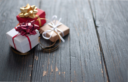 Christmas gift boxes wrapped with ribbon over a wooden backgroundの写真素材