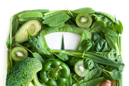 Green fruits and vegetables in the shape of bathroom weighing scales over a white backgroundの写真素材