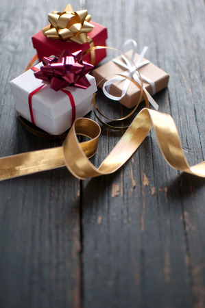 Christmas gift boxes wrapped with ribbon over a wooden backgroundの写真素材