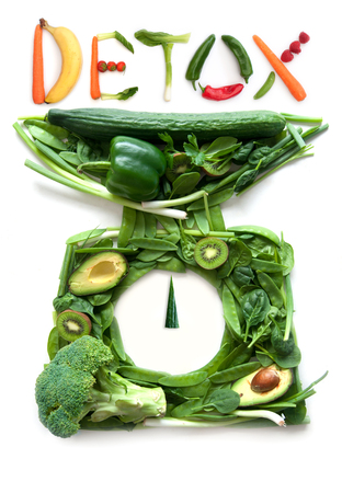 Fruits and vegetables in the shape of kitchen weighing scales with detox on topの写真素材
