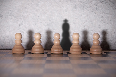 Chess king shadow standing out in a row of pawnsの写真素材