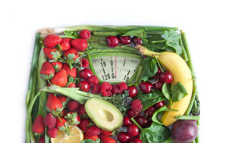 Weighing scales made from fruits and vegetables over a white backgroundの写真素材